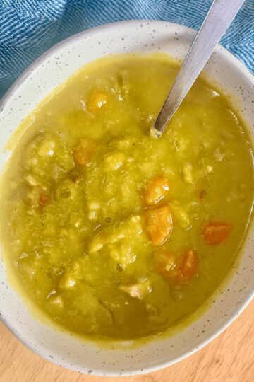 A bowl of split pea soup with a blue napkin.