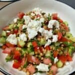 Summer Lentil Salad with feta cheese, tomatoes, cucumbers, and herbs in a white bowl.