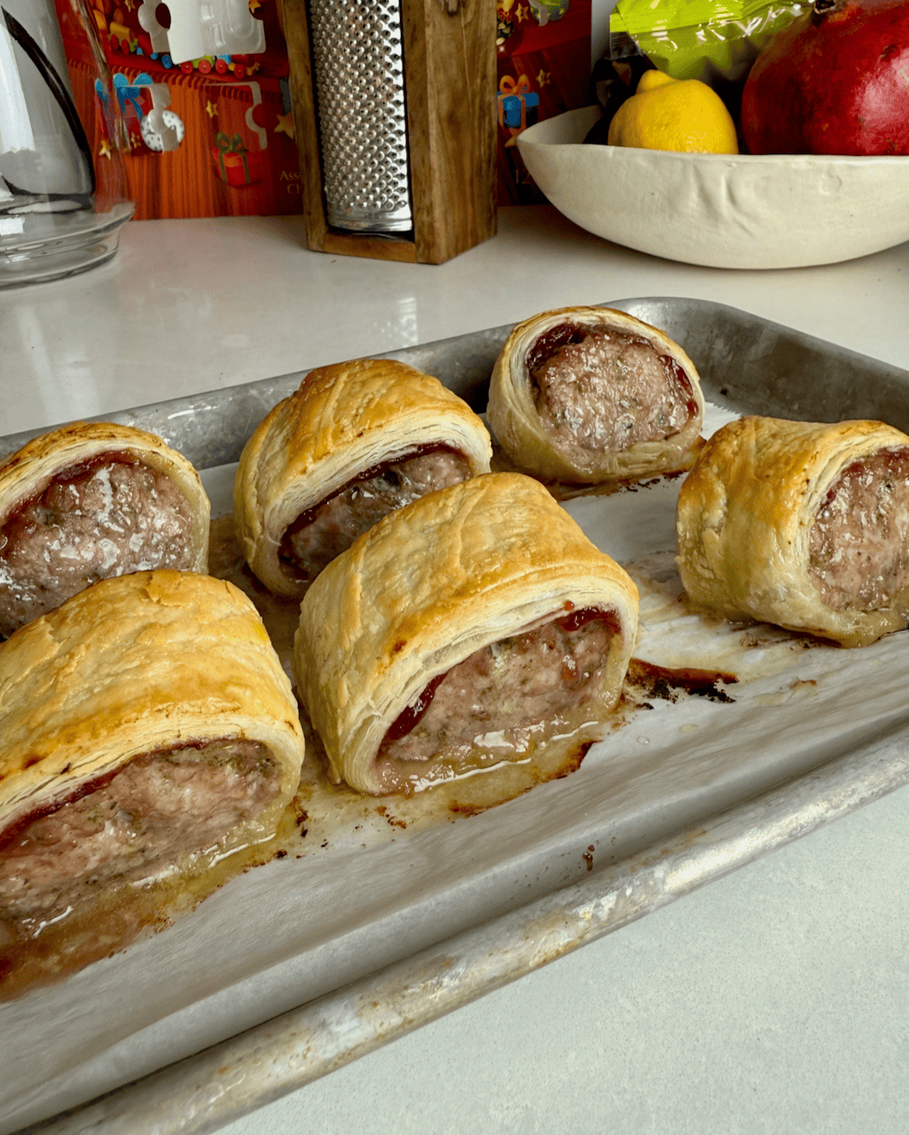 6 baked turkey sausage rolls on a metal baking sheet.