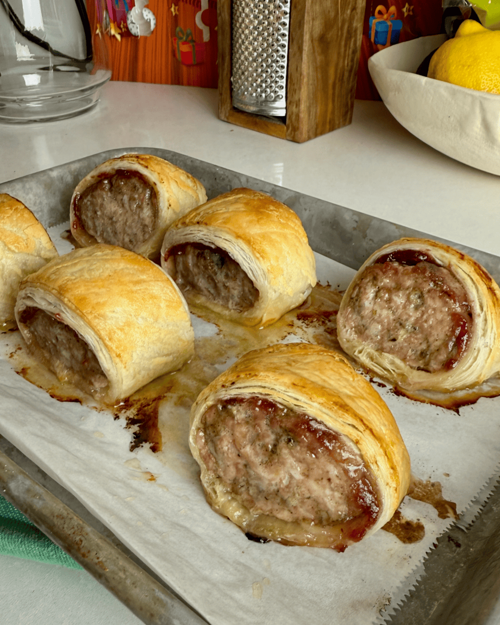 6 baked turkey sausage rolls on a metal baking sheet.