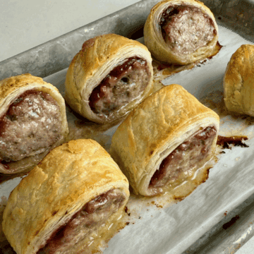 6 baked turkey sausage rolls on a metal baking sheet.