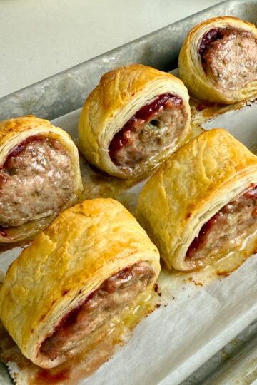 6 baked turkey sausage rolls on a metal baking sheet.