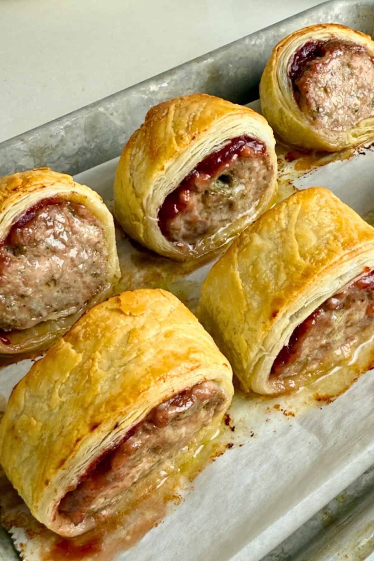 6 baked turkey sausage rolls on a metal baking sheet.