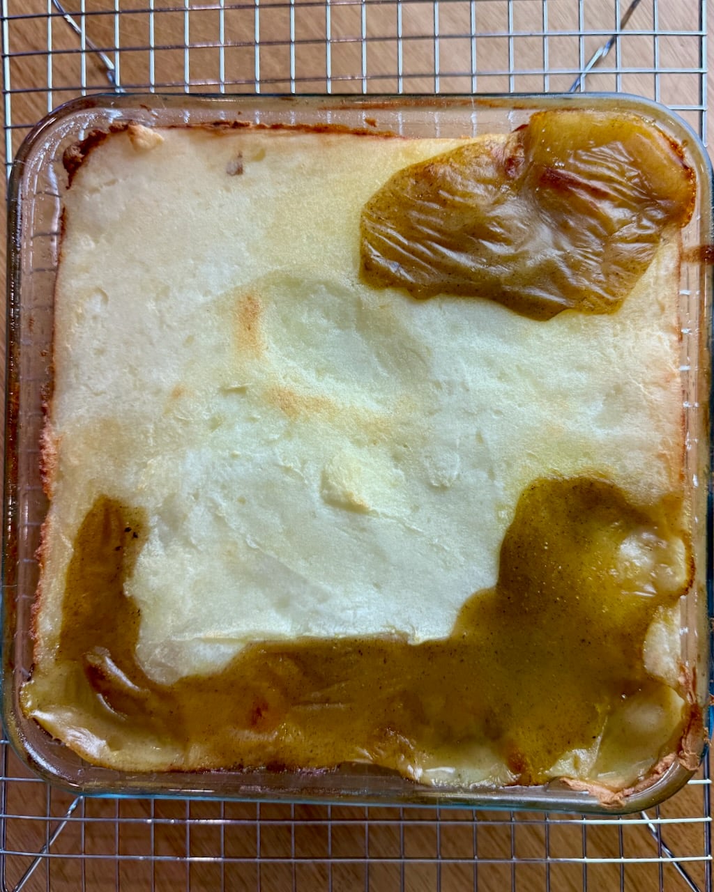 Overhead shot of the bubbling pie in a clear dish, cooling on a rack.