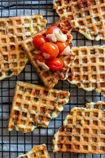 Spinach waffles with cherry tomatoes on a cooling rack.